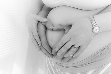 mother's and father's hands making a heart on a pregnant belly mother's and father's hands making a heart on a pregnant belly