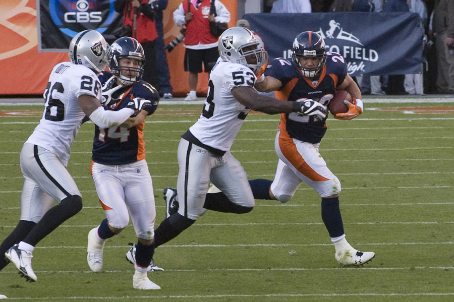 NFL Denver Bronco running back pushing through the Raider's defense at the mile High Stadium in Denver