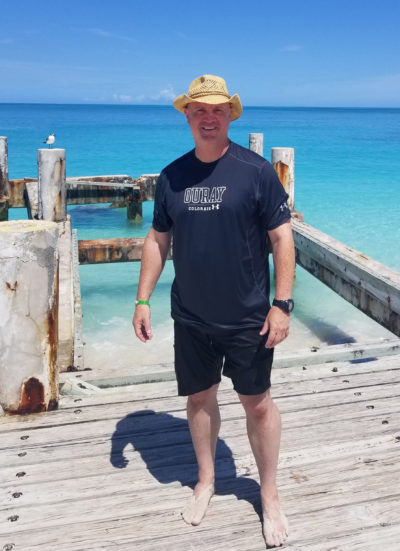 Brody standing on the docks in the Turks and Caicos islands, turquoise water in the background.